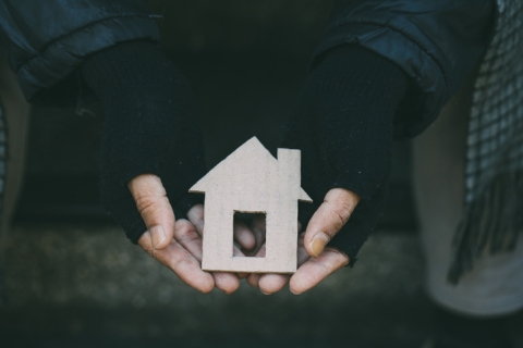 A set of hands hold a cardboard cut out of a house